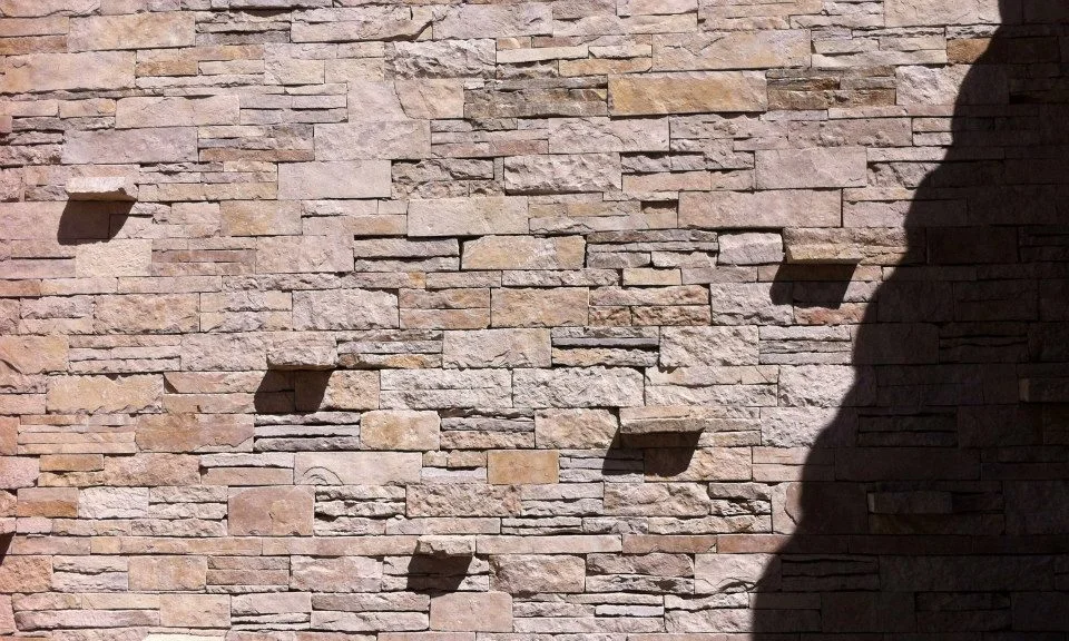 Stone wall set with recessed light niches under raking daylight
