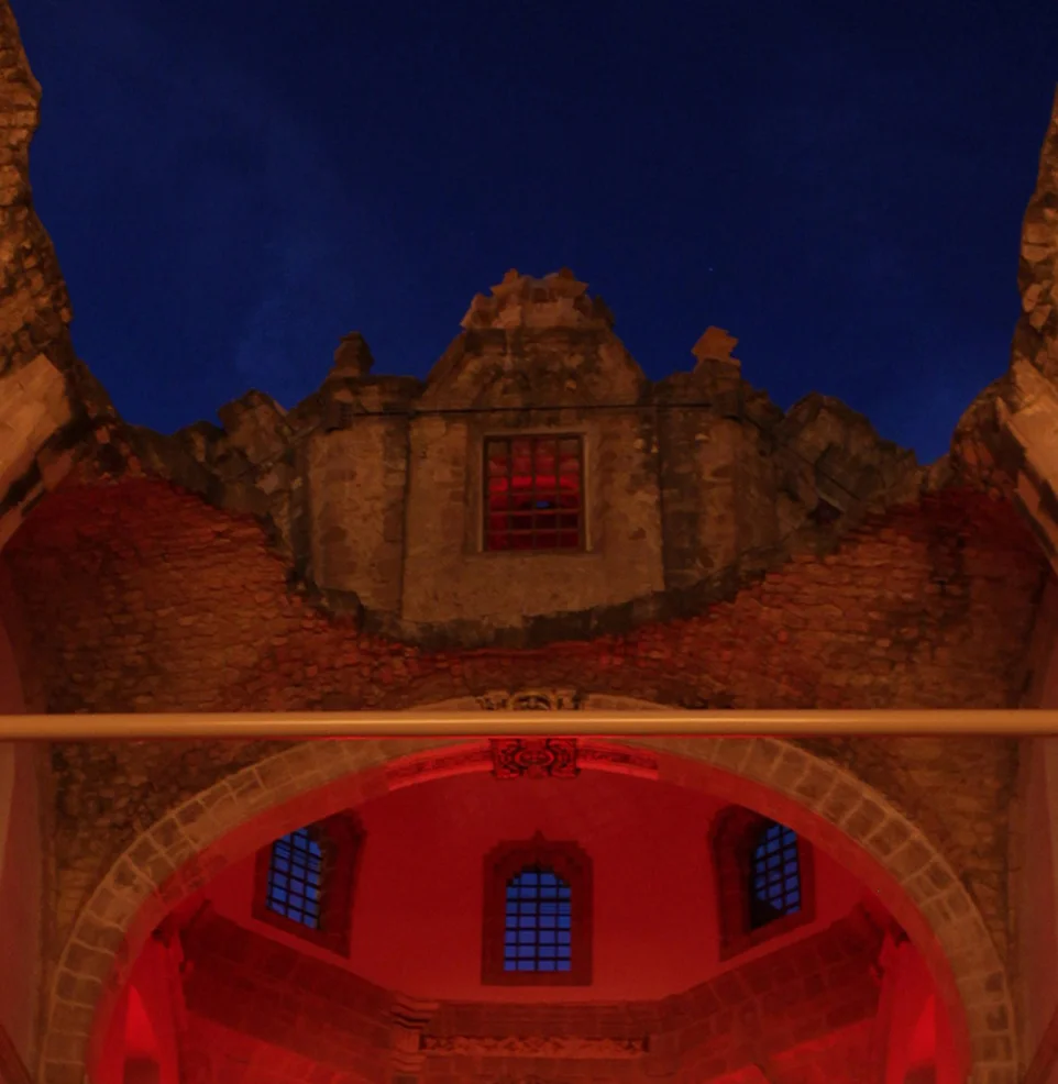 Festival venue exterior at dusk, windows glowing red against a blue sky