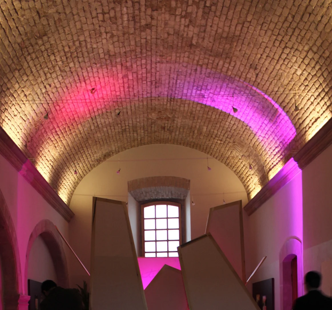 Barrel-vaulted brick ceiling lit magenta above a stair