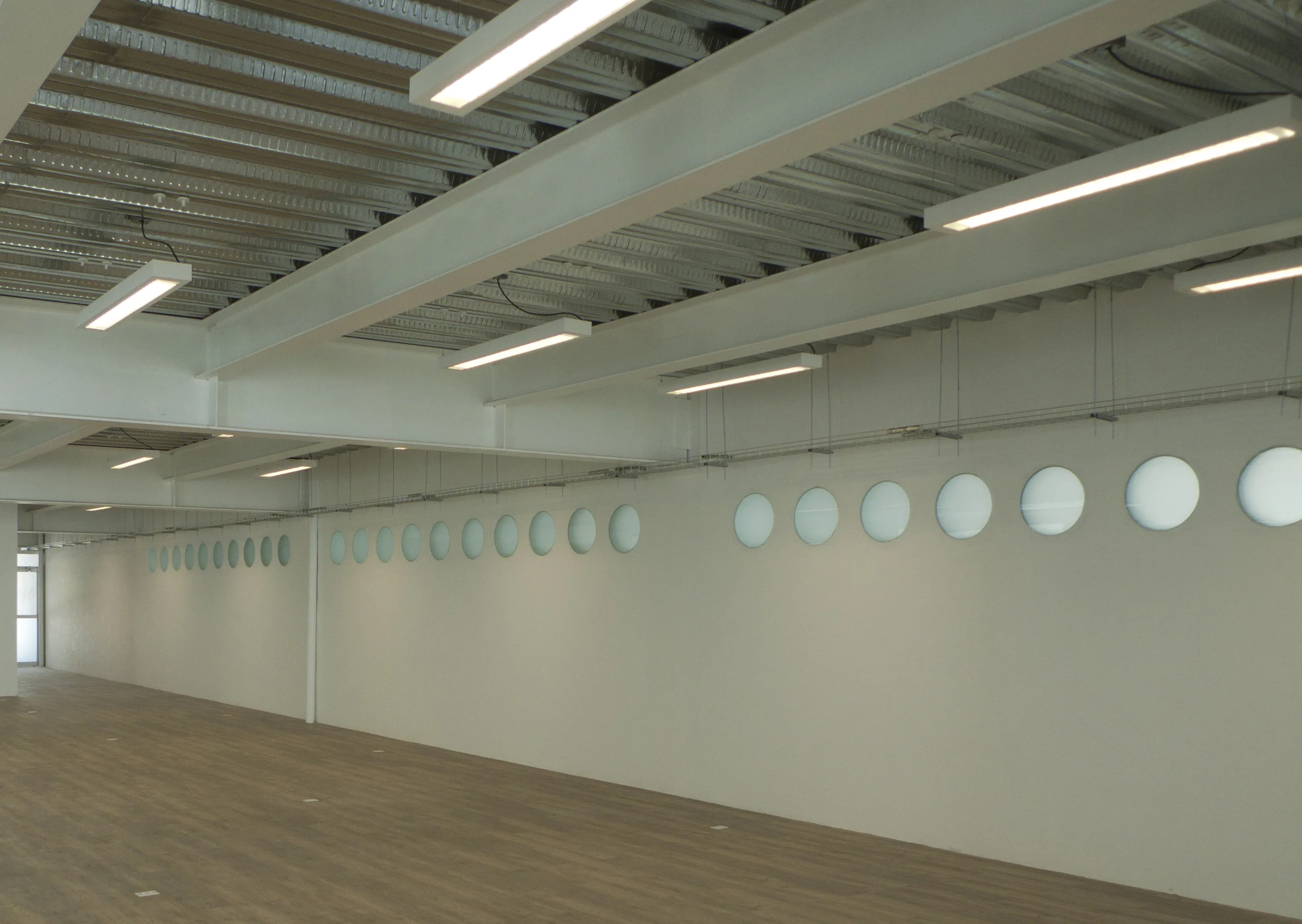 Motolinia University multipurpose area — long hall lit by a wall of translucent discs